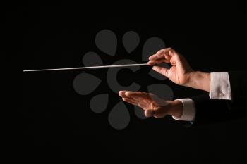 Hands of male conductor on dark background�