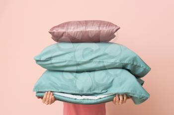 Woman with soft pillows on color background�