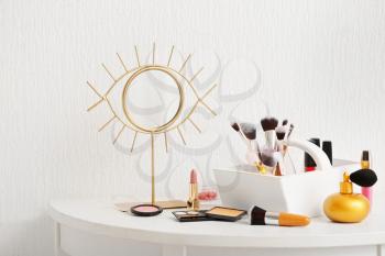 Set of makeup cosmetics with brushes and mirror on table�