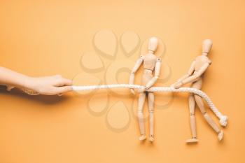 Female hand and wooden human figures pulling rope on color background. Unity concept�