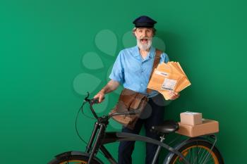 Surprised old postman with bicycle on color background�