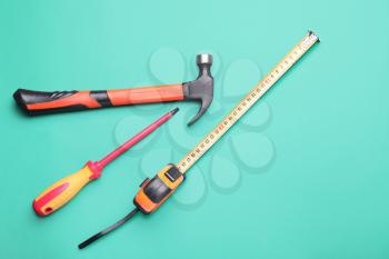 Measuring tape with builder's supplies on color background�