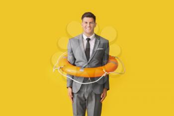 Young businessman with lifebuoy on color background�