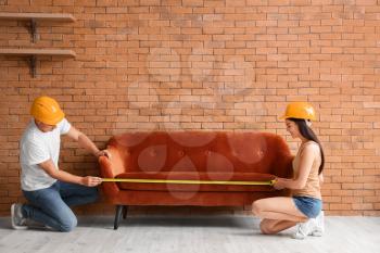 Couple with measuring tape near sofa in room�