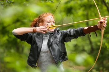 Sporty young woman practicing archery outdoors�