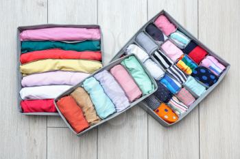 Organizers with clean clothes on wooden floor�