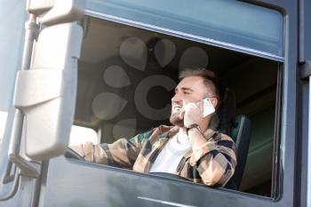Young man talking by phone while driving modern truck�