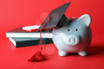 Piggy bank with graduation hat on color background�