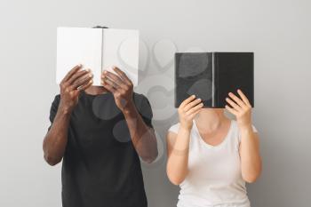 Caucasian woman and African-American man with books on grey background. Racism concept�