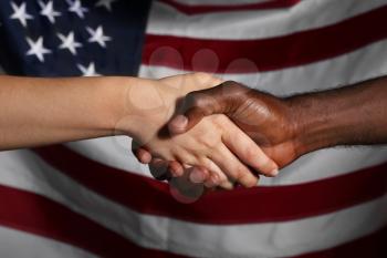 Caucasian woman and African-American man shaking hands near national flag of USA. Racism concept�