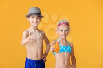 Little children with sun protection cream on color background�