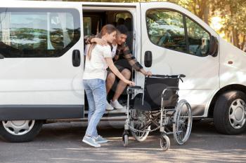 Woman helping her handicapped husband to get out of van�