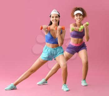 Young women doing aerobics on color background�