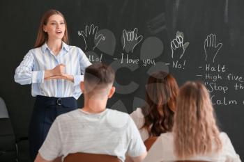 Teacher conducting courses for deaf mute people in classroom�