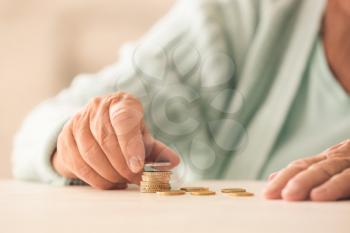 Senior woman counting coins on table. Concept of pension�