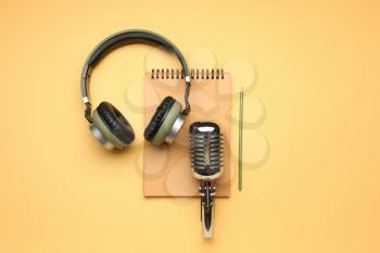 Headphones with microphone and notebook on color background�