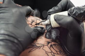 Professional artist making tattoo in salon�