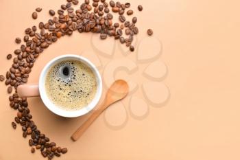 Cup of hot coffee and beans on color background�