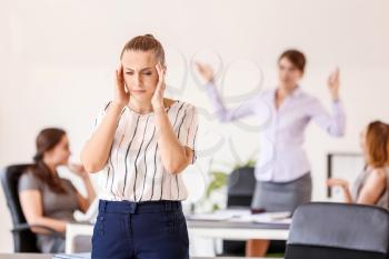 Stressed woman with headache and noisy people in office�
