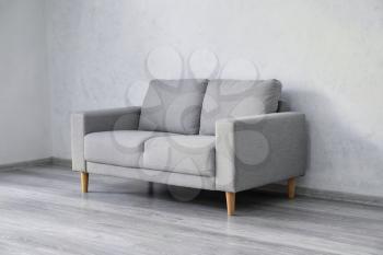 Stylish cozy sofa near light wall�