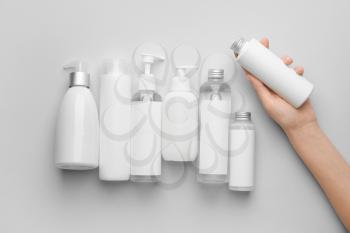 Female hand with cosmetic bottles on light background�