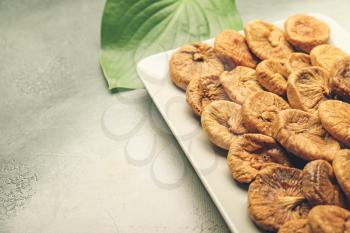 Plate with tasty dried figs on color background�