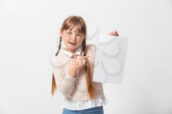 Little girl with blank paper sheet on light background�