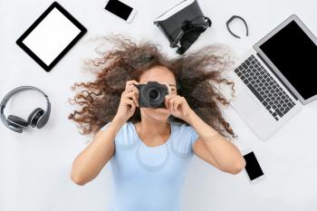 Young woman with different gadgets and photo camera on white background�