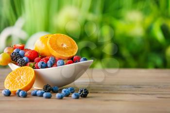 Bowl with different fruits and berries on table outdoors�