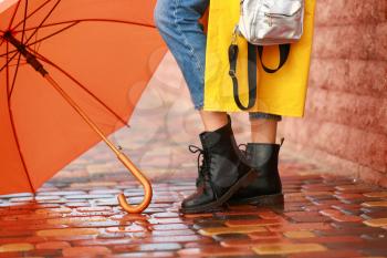 Beautiful young woman with umbrella wearing raincoat outdoors�