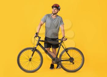 Male cyclist with bicycle on color background�