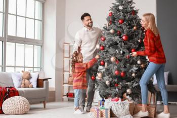 Young family decorating Christmas tree at home�