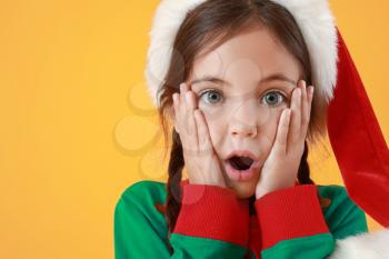 Surprised little girl dressed as elf on color background�
