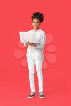 Teenage African-American girl with laptop on color background�