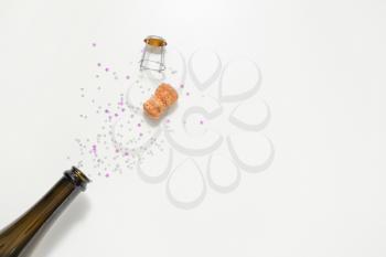 Open bottle of champagne and glitters on white background�