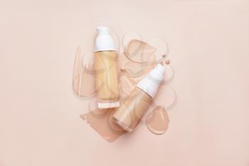 Bottles of makeup foundation and samples on color background�