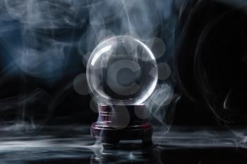 Crystal ball of fortune teller in smoke on dark background�