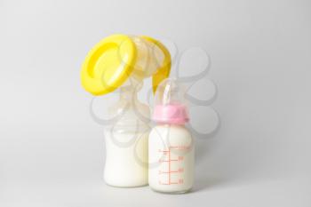 Breast pump and bottle of milk on grey background�