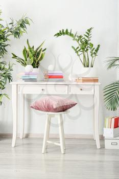Books on table and houseplants in interior of light room�