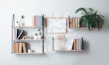 Shelves with books and decor hanging on light wall�