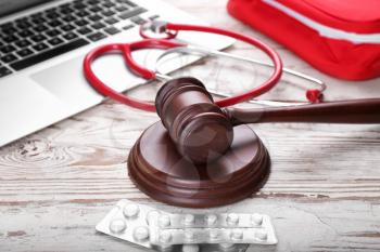 Judge gavel, pills, laptop and stethoscope on wooden background. Concept of health care reform�