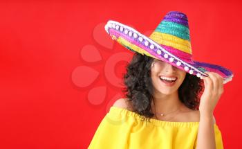 Beautiful woman in sombrero hat on color background�