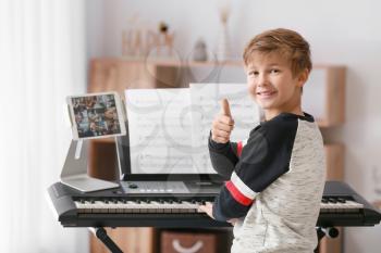 Little boy taking music lessons online at home�