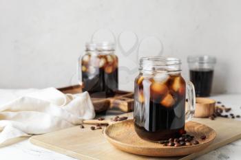 Mason jars of tasty cold brew and coffee beans on white background�