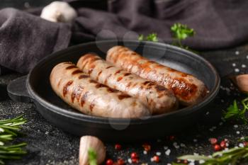 Frying pan with delicious grilled sausages on dark background, closeup�