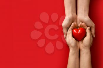 Hands with red heart on color background�