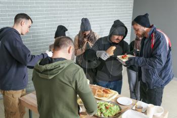 Volunteers giving food to homeless people in warming center�