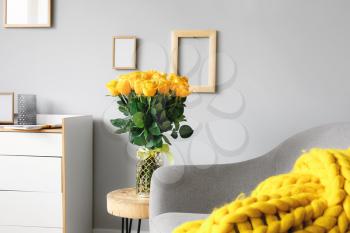Vase with beautiful yellow roses on table in interior of room�