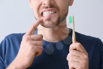 Man with aching teeth and brush on grey background�