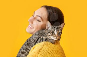 Young woman with cute cat on color background�